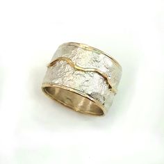 This is a wide, bold ring, chunky but not heavy, that makes a statement. It has a crumpled tinfoil texture with a wavy gold stripe soldered on top. Width: 0.56 inch / 14 mm Thickness: 0.1 inch / 2.5 mm This listing is for sizes 4-13- Just convo me your size. For other sizes - please convo me. Additional information If you liked this item, you may also want to look at these pieces: http://etsy.me/2fWkafJ http://etsy.me/2eI2vT3 For customer reviews of our shop: http://etsy.me/2eOQZZt Back to our s Unique Hammered Rings With Thick Band, Unique Hammered Wide Band Rings, Elegant Wide Band Hand Cast Jewelry, Elegant Hand Cast Wide Band Jewelry, Wide Band Silver Hammered Jewelry, Hammered Thick Band Wide Ring For Promise, Hammered Wide Band Ring For Promise, Hammered Wide Band Ring As Gift, Unique Hammered Gold Wide Band Ring