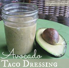 an avocado sitting on top of a green table next to a jar of dressing