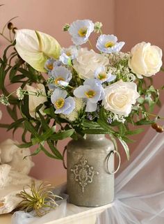 a vase filled with white and blue flowers sitting on top of a table next to a teddy bear