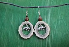 the earrings are decorated with an animal and beaded in silver wire on a green background