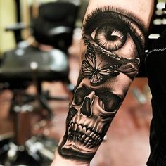 a man's arm with a skull and eye tattoo on it