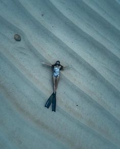 a woman laying on top of a sandy beach