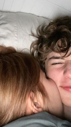 a young boy laying in bed with his head on the back of a woman's shoulder