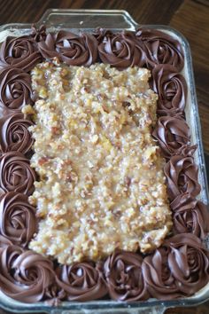 a chocolate cake with frosting and nuts in it on a wooden table top,