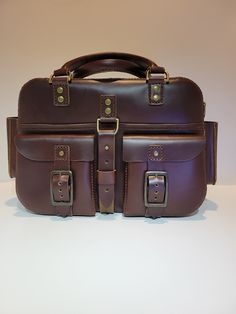 "A beautiful handmade handbag. It is made out of Redwood, pull-up style leather. It is hand cut and hand sewn. It has 2 front pockets, 2 pouches (1 on each end), a full length back pocket, an inside divider, a full length top zipper, 2 handles and a detachable shoulder strap.  All the hardware is antique brass.  The pouches will hold a cell phone.  Front pockets have buckle closures for more security. Making it harder for smaller items to fall out. Size: H 9\" X L 14\" X W 6\"" Full Length Top, Handmade Handbag, A Cell, Handmade Handbags, The Pouch, Pull Up, Pull Ups, Up Styles, Hand Sewn