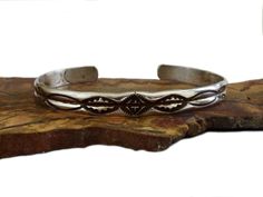 Vintage Navajo hand tooled sterling silver cuff bracelet. Deep cleft down the middle with stampings on each side. Signed with a curved M. Marked Sterling. Great for stacking. Measures 1/4" wide with a 2mm thickness. Inner circumference 5 3/4" with 1" gap. Weighs 9.89g. All measurements approximate. Band has some flexibility. Estate auction find; good vintage condition, some tarnish.  👉🏻To continue browsing in the shop please click this link: https://www.etsy.com/shop/SumpnSassyVintage I do not polish my vintage silver as some people like the aged patina. If you want me to polish it before shipping, just let me know! I am not an expert on vintage jewelry, but I do buy and sell what I love! Since these items are vintage, they may have a wonderful aged patina and are not meant or expected t Western Style Stamped Cuff Bracelet, Southwestern Style Adjustable Stamped Bangle, Vintage Silver Hand-tooled Cuff Bracelet, Vintage Silver Hand Tooled Cuff Bracelet, Sterling Silver Cuff Bracelet, Vintage Navajo, Sterling Silver Cuff, Silver Cuff Bracelet, Silver Cuff