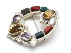 "-Intricate design Scottish brooch -Faceted oval cairngorm citrine, purple glass stones, and various agates adorn this pin -Pin is Sterling Silver, fine detailed silver work -Straight pin with rolling ball close -Stones measure 15mm x 12mm, 13mm x 10mm, and 10mm x 8mm -Agates measure roughly 8mm x 6mm -Pin measures roughly 2\" X 2.3\" -Weight 23.9g -Excellent vintage condition, ready to wear, silver has not been cleaned Very unique one of a kind piece to add to your collection" Formal Multicolor Gemstone Brooches, Antique Multi-stone Brooches For Formal Occasions, Antique Oval Gemstone Brooch, Antique Oval Gemstone Brooches, Collectible Round Gemstone Brooch, Collectible Round Gemstone Brooches, Ornate Gemstone Brooches For Collectors, Round Multi-stone Brooch As Gift, Unique Multi-stone Brooches For Gift