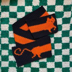 two black and orange knitted animal mitts on a green and white checkered blanket