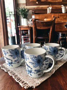 four blue and white coffee cups sitting on top of a wooden table next to a chair