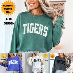 "Unleash the Spirit with Our Custom Tigers Mascot Comfort Colors Sweatshirt." This sweatshirt brings school pride and team spirit to a whole new level. With our custom mascot design, you can proudly represent your school or organization wherever you go. Made with the finest Comfort Colors fabric, it offers unparalleled comfort and durability. Whether you're cheering from the stands, on the field, or simply hanging out with friends, this sweatshirt is your ultimate go-to for coziness and style. S Green Letter Print Top For College, Green Casual Sweatshirt For School, Cotton Campus Tops With Team Name, School Spirit Tops With Text Print For Campus, Campus School Spirit Tops With Text Print, School Spirit Tops With Letter Print For Campus, School Spirit Letter Print Tops For Campus, Collegiate Tops For School In Fall, Campus Letter Print Tops With School Spirit