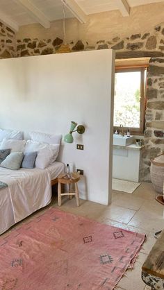 a bedroom with stone walls and a pink rug on the floor in front of it