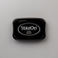 the stazon ink pad is black and has white lettering on it, which reads'stazon '