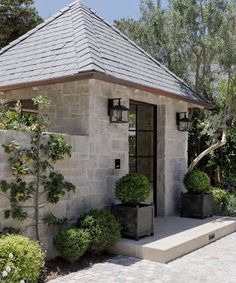 a small stone building with potted plants in the front and on the outside side