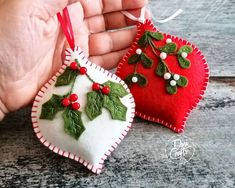 two handmade christmas ornaments in the shape of heart with holly leaves and berries on them