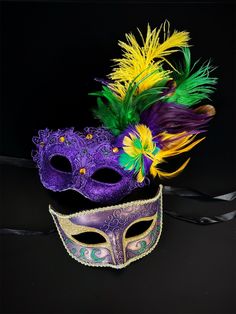 two masquerade masks with feathers on black background