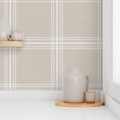 a white vase sitting on top of a wooden shelf next to a cup and saucer