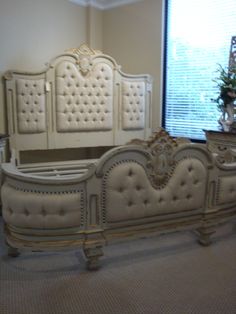 a white bed sitting in the middle of a room next to a wall with a window