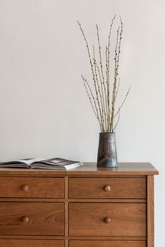 a vase filled with flowers sitting on top of a wooden dresser