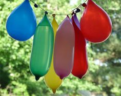 colorful balloons hanging from a string in front of trees