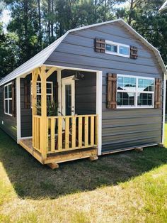 a small house with a porch on the grass