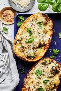 two stuffed sweet potatoes with spinach and cheese on a blue plate next to silverware