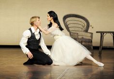 a man kneeling down next to a woman in a white dress