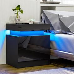 a bed with a blue light on the side and a night stand next to it