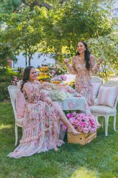 two women sitting at a table in the grass