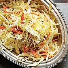 a bowl filled with coleslaw and carrots on top of a table