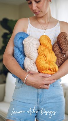 a woman holding several skeins of yarn in her hands