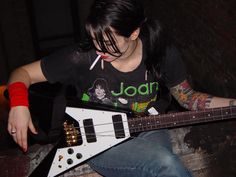 a woman with tattoos playing an electric guitar