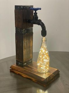 a bottle with some lights in it sitting on top of a wooden stand next to a faucet