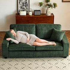 a woman laying on top of a green couch