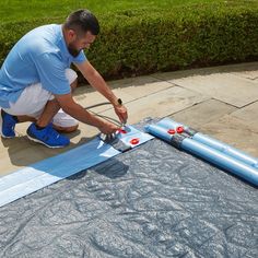 a man in blue shirt and white shorts working on a piece of art with scissors