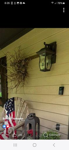 an american flag is hanging on the side of a house with a wagon and lantern