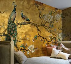 two peacocks are sitting on a tree branch in front of a gold wall mural