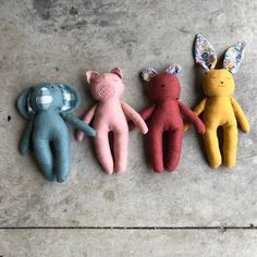 four stuffed animals are lined up in a row on the concrete floor, one is wearing bunny ears