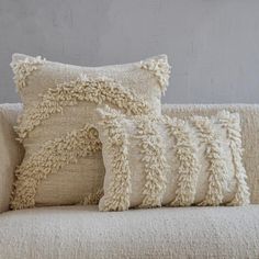 two pillows sitting on top of a white couch