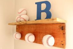 a wooden shelf with baseballs on it and the letter b in blue is mounted to the wall