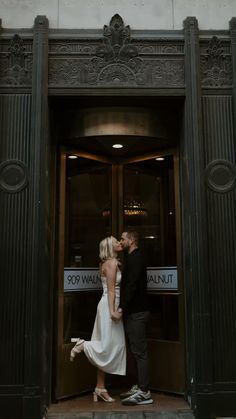 a man and woman kissing in front of an entrance to a building with the words do you want it?