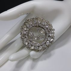 *Description: This is a gorgeous clear rhinestone wedding brooch from the 1960s. The two tiered design has clear rhinestones in teardrop cuts and chaton cuts throughout. The center of the brooch is open and there are three sets of rhinestones which look like flowers on a silver tone stem. This brooch would be a great to wear to a wedding or give the bride as an heirloom gift. It would be beautiful to wear to any special occasion. This brooch would be a great addition to your vintage jewelry coll Glamorous Silver Brooch For Wedding, Vintage Sparkling Wedding Brooches, Wedding Costume Jewelry Brooches With Sparkling Stones, Wedding Silver Brooches With Sparkling Stones, Glamorous Rhinestone Wedding Brooches, Brooch Wedding, Formal Earrings, Vintage Christmas Gifts, Heirloom Gifts