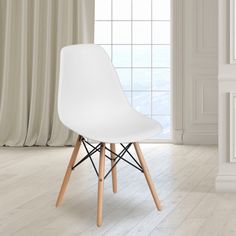 a white chair sitting in front of a window next to a wooden table and fireplace