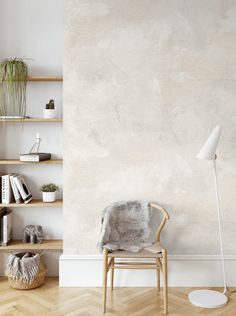 an empty room with a chair, bookshelf and plant on the wall next to it