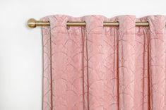 pink curtains hanging on the side of a white wall with gold metal rods and handles