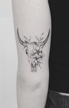 a black and white photo of a bull skull with flowers on it's side