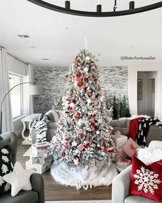 a christmas tree in the middle of a living room decorated with red and white ornaments