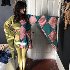 a woman standing in front of a bed holding up a colorful blanket