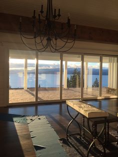 an empty room with large windows overlooking the water and mountains is pictured in this image