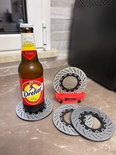 a bottle of beer sitting next to three disc coasters on top of a counter