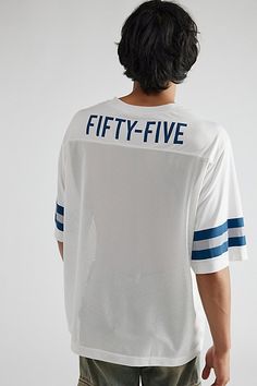 the back of a man wearing a white shirt that says fifty five in blue on it